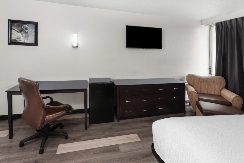 King bed guest room with work desk, dresser and HDTV at Travelodge by Wyndham Milwaukee