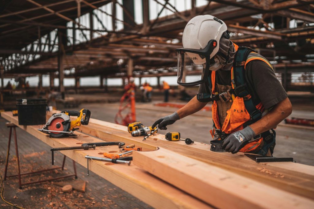 Construction worker drilling lumber on a job site — crew lodging near Milwaukee job sites at Travelodge by Wyndham Milwaukee